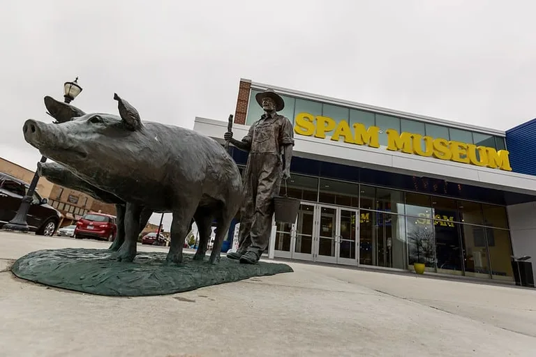 A statue of a farmer and pig in front of the Spam Museum.