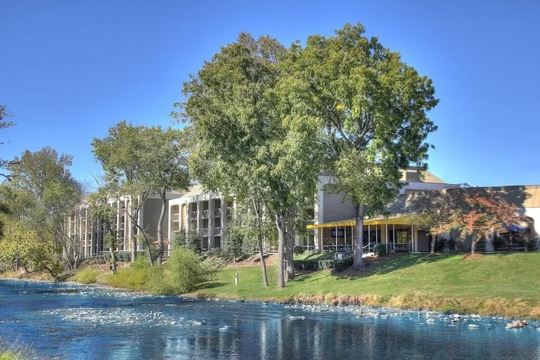 A view of the Inn on the River, Pigeon Forge, with trees and a bright river.