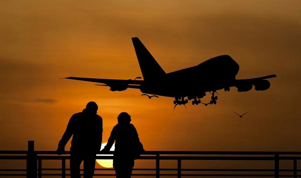 Silhouette of a couple watching a plane taking off.